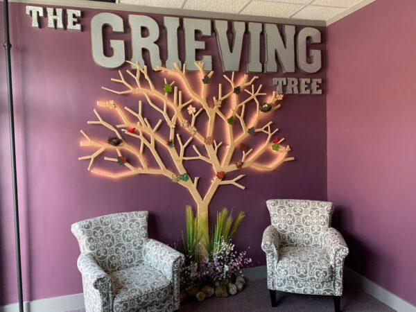 The Grieving Tree display with chairs and memorial wall decor.