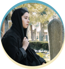 Woman in hijab thoughtful in cemetery.