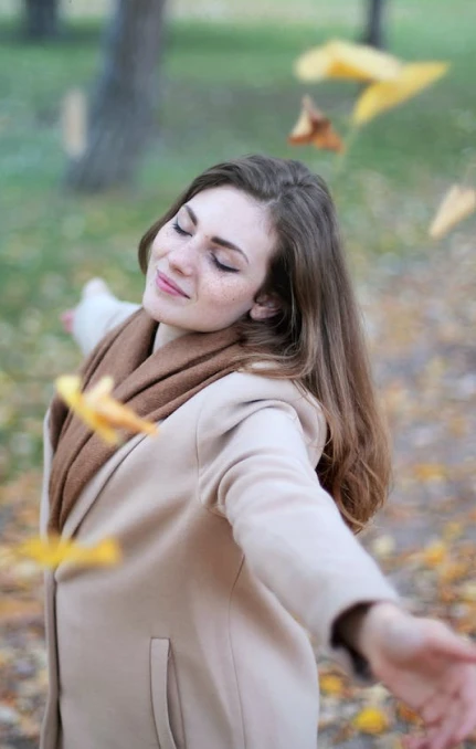 Woman enjoying autumn leaves in a park.