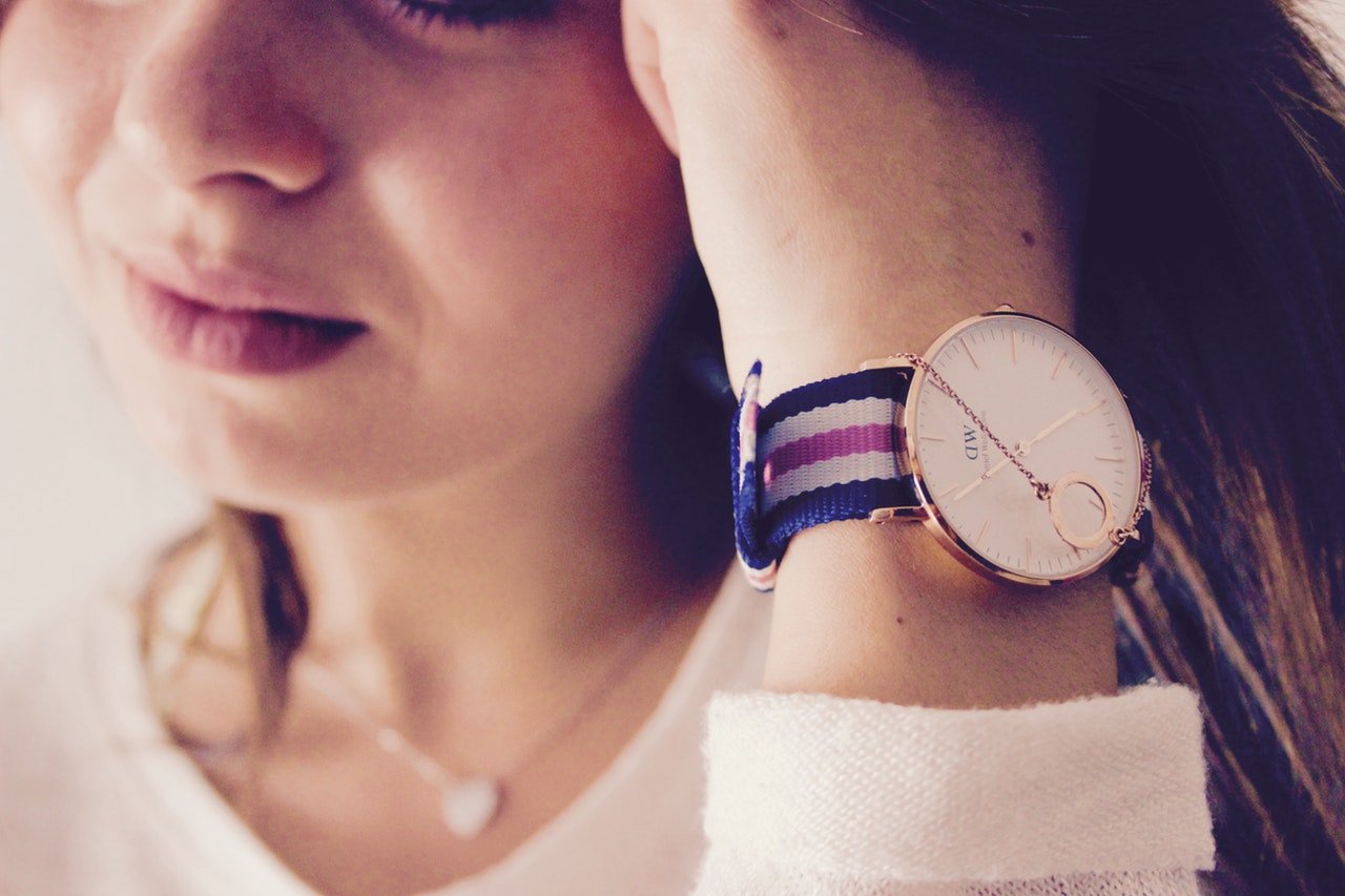 Woman wearing stylish wristwatch with striped band.