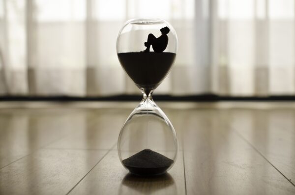 Hourglass with silhouette on wooden floor.